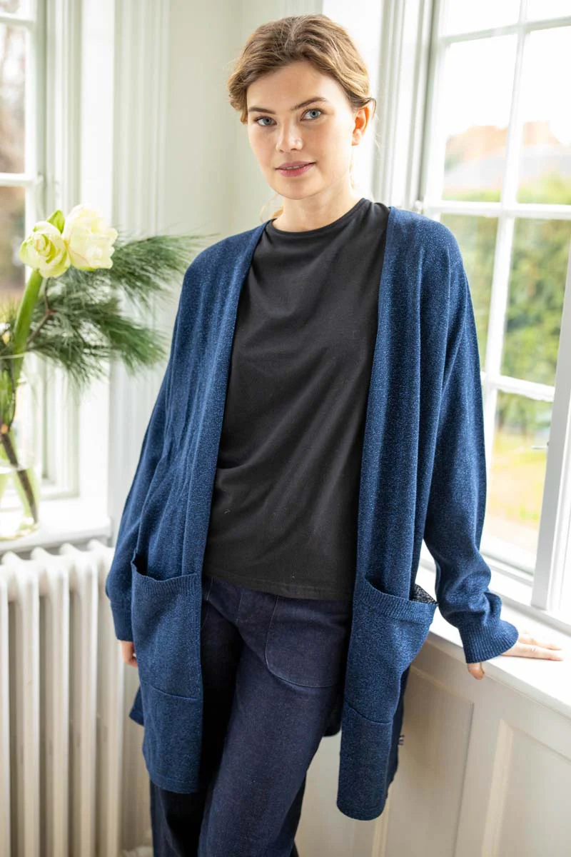 Danefae-Danoffice Glitter Cardigan Dk Navy Lange Strickjacke mit großen Taschen. Schöne Farbe mit Glitzer. Schöne Baumwollqualität. Office Cardigan ist eine schöne, lange Strickjacke in angenehmer Baumwollqualität. Die Strickjacke ist schön schlicht und hat große Taschen. Die Kombination aus schöner Farbe und feinem Glitzer macht die Strickjacke perfekt, um grauen Tagen Farbe zu verleihen. Tragen Sie sie über einer Hose oder einem Kleid. Der Office Cardigan besteht aus einem schönen Baumwollstrick aus 90 % Baumwolle und 10 % Lurex. Das Material ist Öko-Tex-zertifiziert.