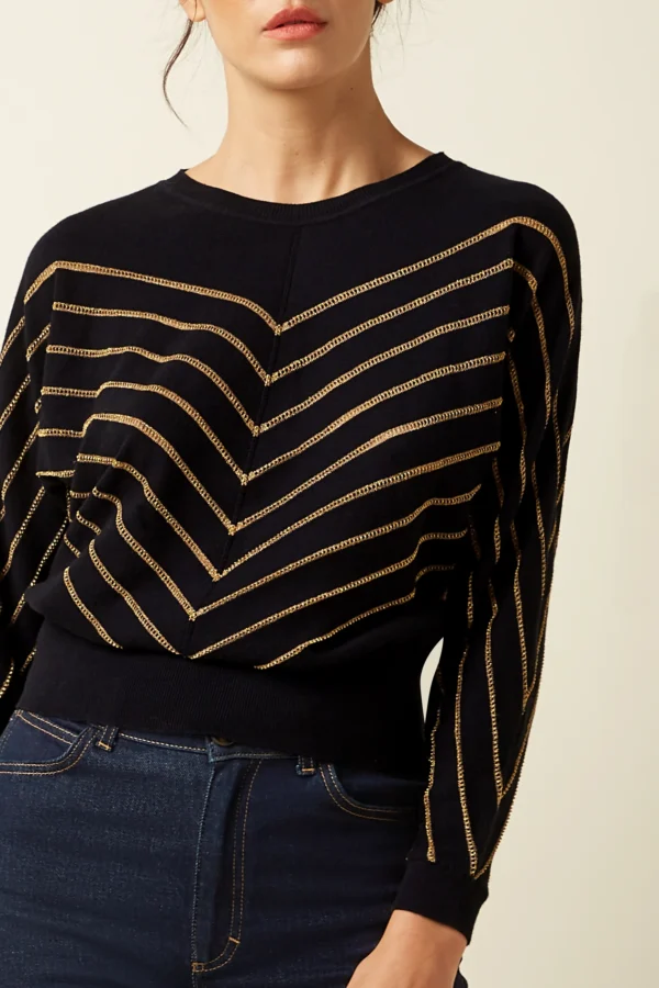 Zeitloser, locker sitzender Stricktop mit elegantem Schlaufenverschluss am Rücken. Aus Baumwolle, Kaschmir und goldenem Lurex gefertigt.