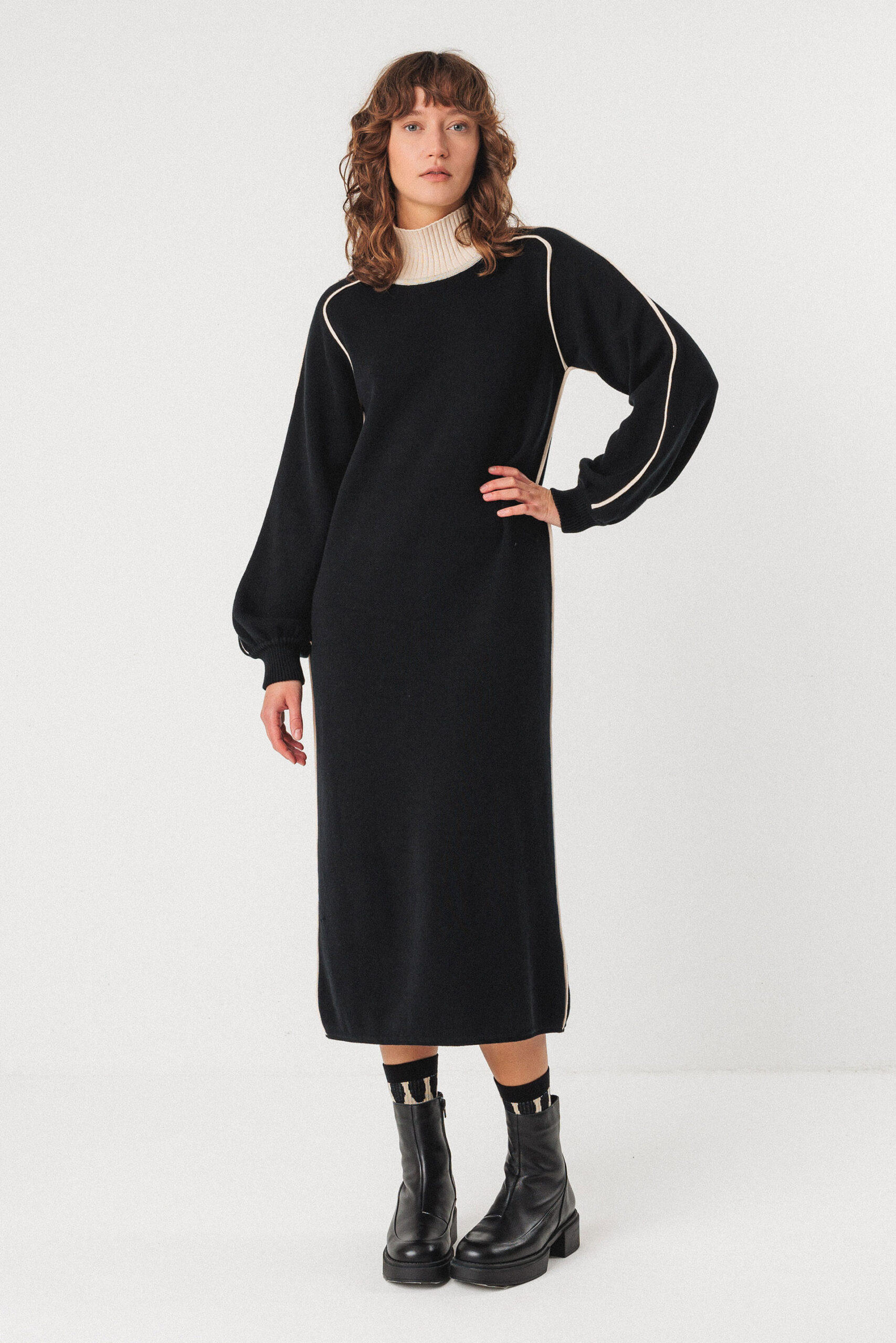 Mittellanges Kleid aus mittelschwerem Bio-Baumwollstrick. Mit Kontrastpaspeln und hohem Kragen aus passendem Rippstrick. Gerader Schnitt mit langen Ballonärmeln.
